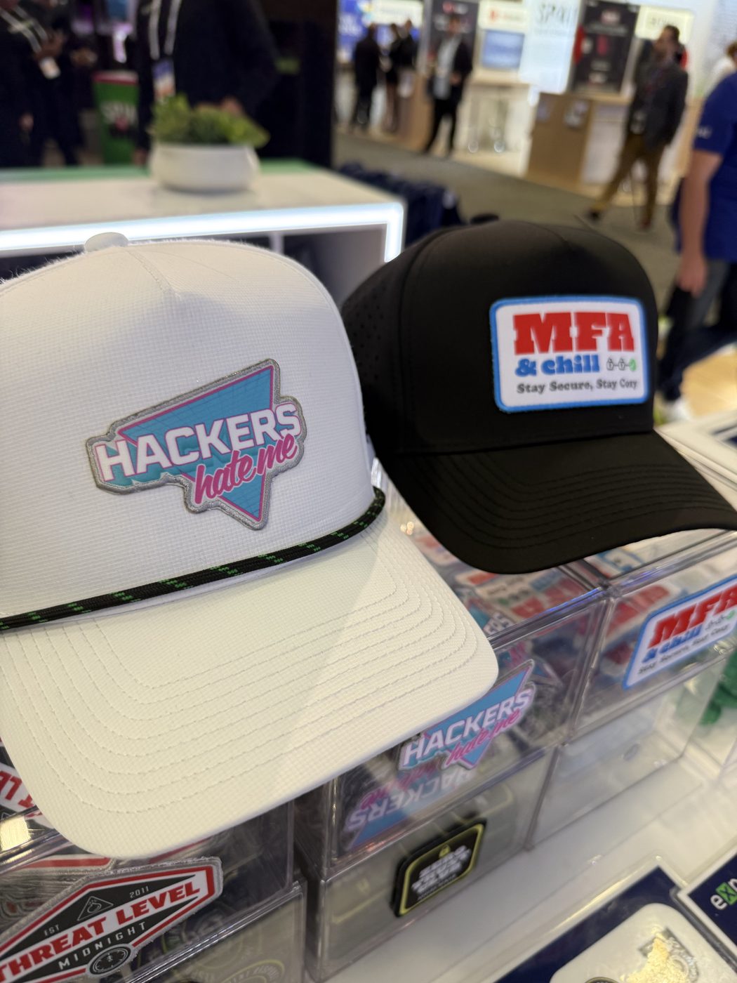 A white Hackers Hate Me hat and a black MFA and Chill hat